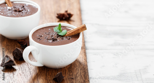 Hot chocolate drinks and chocolate pieces in white cup.