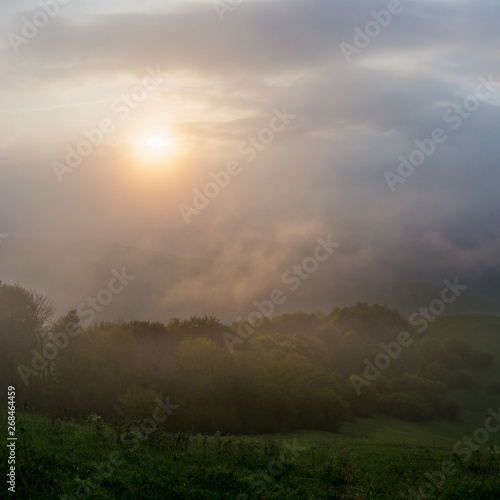 The rising sun lightening the mountain range through the clouds