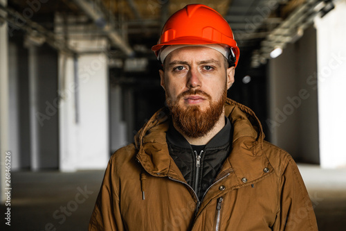 The average plan portrait of an adult man in a helmet with redhead, evaluates, studies, looks into the frame, horizontal, free space and perspective