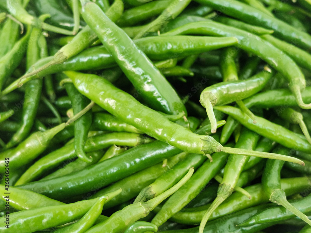 Green hot spicy chili peppers at the market counter Green hot spicy chili peppers at the market counter