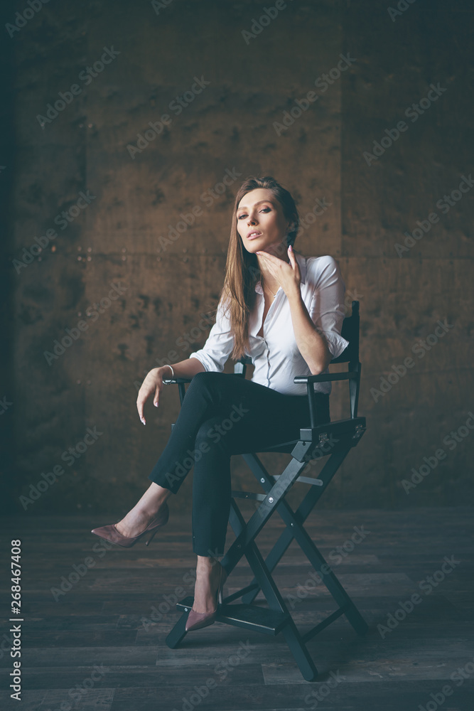 An actress. Portrait of young beautiful emotional sensual woman in white shirt sitting on chair. An actress. Portrait of young beautiful emotional sensual woman in white shirt sitting on chair.
