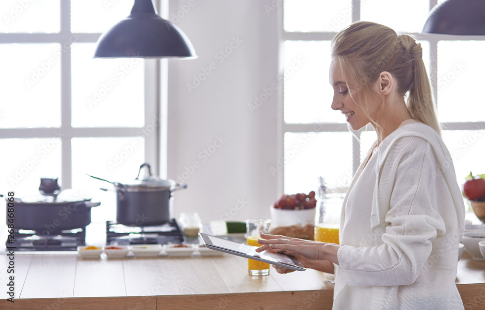 beautiful young woman using a digital tablet in the kitchen beautiful young woman using a digital tablet in the kitchen