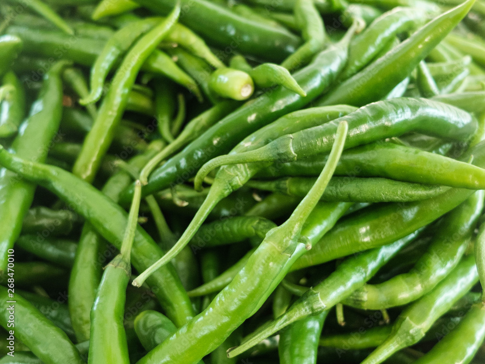 Green hot spicy chili peppers at the market counter Green hot spicy chili peppers at the market counter