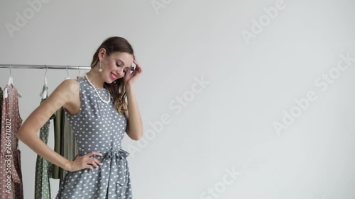 Stylish and fashionable girl model posing in a polka dot dress and spinning next to the clothes hanger on a white background. Slow mo