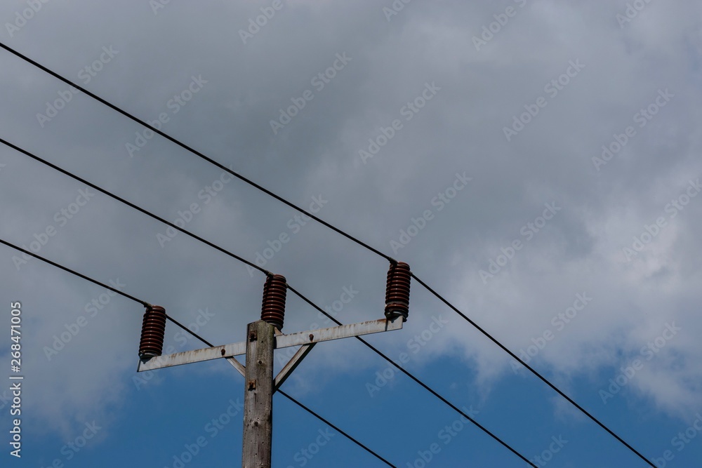 Power cables seen against a blue sky with white clouds