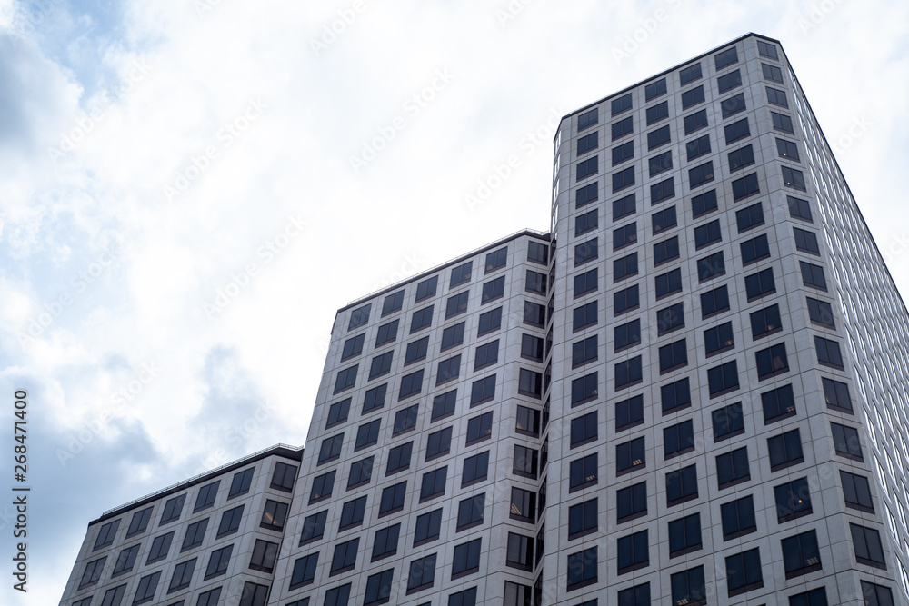 Low Angle Of Modern Glass Skyscraper Against Vivid Blue Sky with Clouds Low Angle Of Modern Glass Skyscraper Against Vivid Blue Sky with Clouds