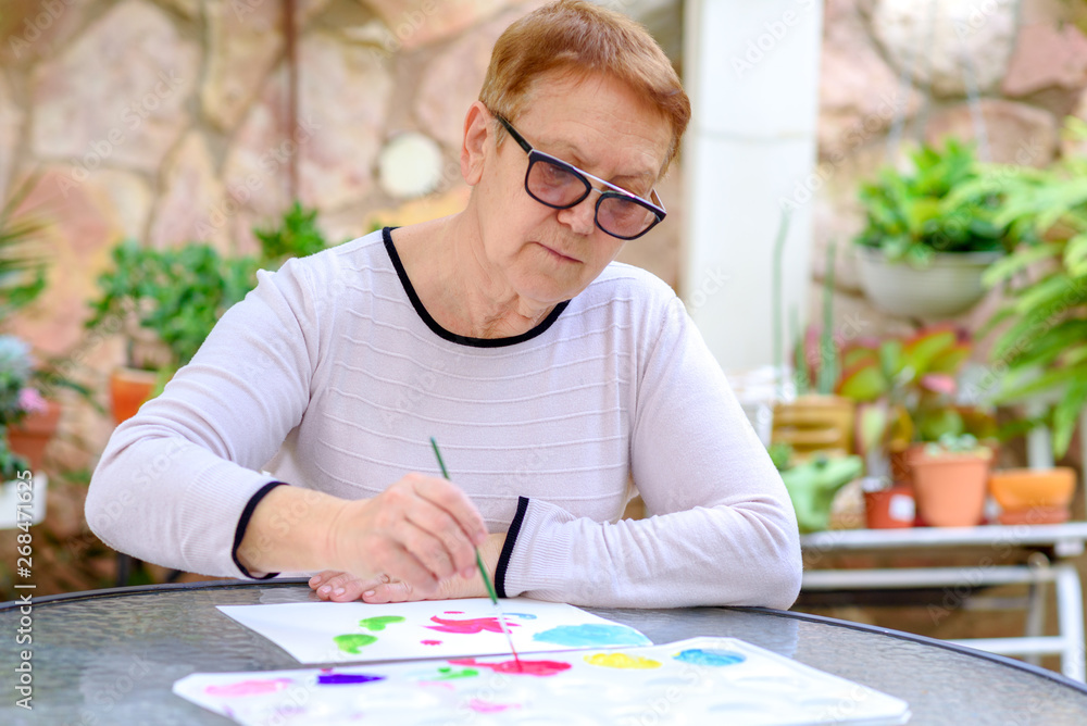 Happy authentic woman senior painting in summer garden. Happy authentic woman senior painting in summer garden.