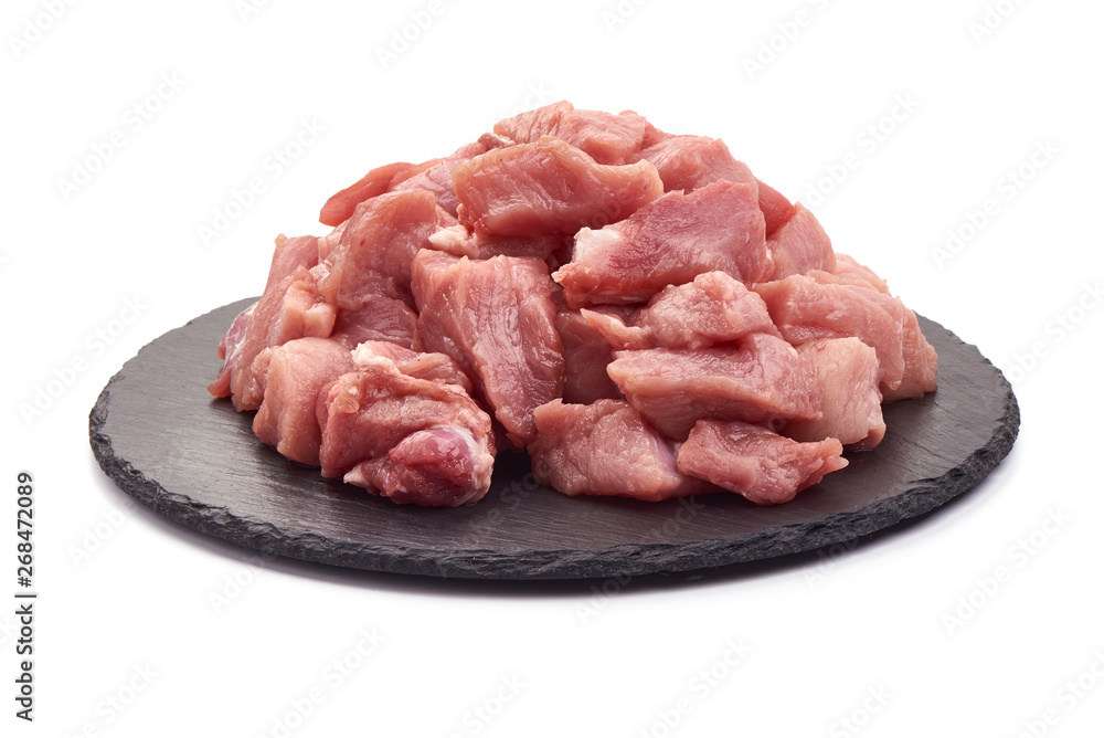 Raw pork pieces on a slate shale plate, close-up, isolated on white background