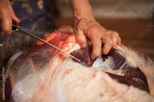 Mature woman cuts a piece of meat with a knife