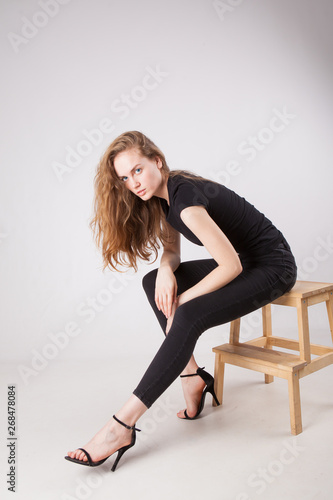 thin young woman in black clothes on a light background