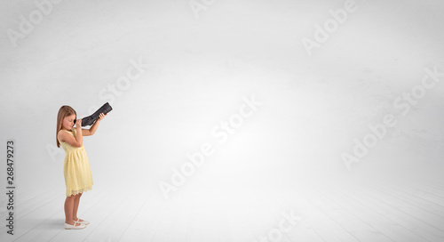 Cute little girl looking through spyglass to an empty space  © ra2 studio