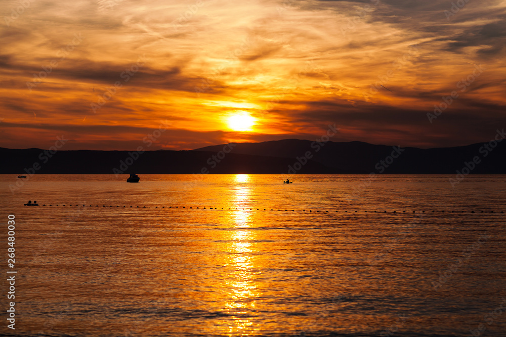Fototapeta premium Orange sunset on the sea with the sun, a beautiful sky on the background of mountains