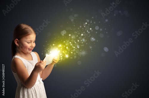 Little cute girl playing on sparkling tablet 