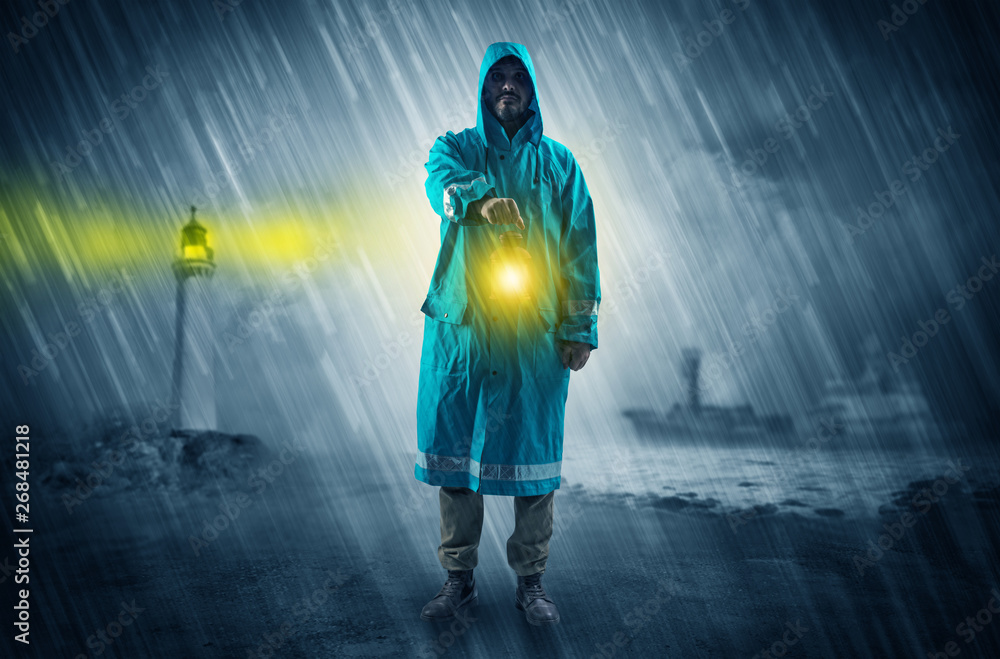 Fototapeta premium Man at the coast coming in raincoat with glowing lantern concept 