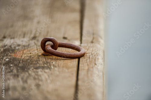 Canvastavla Wooden deck of a pier with a worn, rusty metal ring for mooring a boat