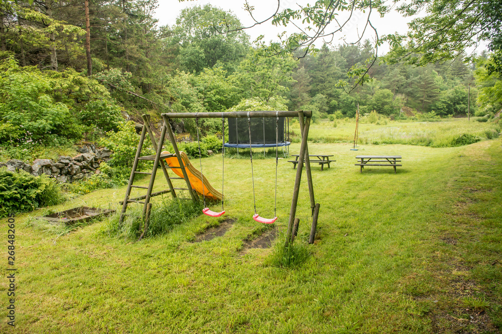A small playground with swings, benches and a trampoline. A small playground with swings, benches and a trampoline.