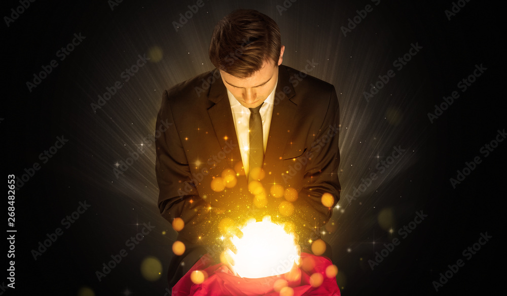 Fototapeta premium Gorgeous businessman sitting with sparkling magic ball in his lap 