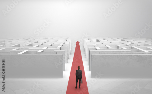 Businessman going straight ahead on a red carpet arrow between two maze
