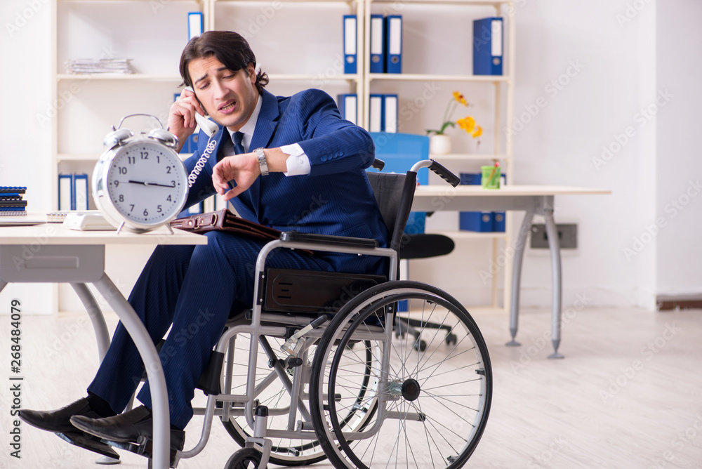 Young male employee in wheelchair working in the office 