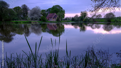 Reflections of St Leonard's church in Hartley Mauditt Pond, South Downs National Park, UK photo