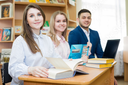 A group of happy students with books sitting at a table in the University library. The concept of education.