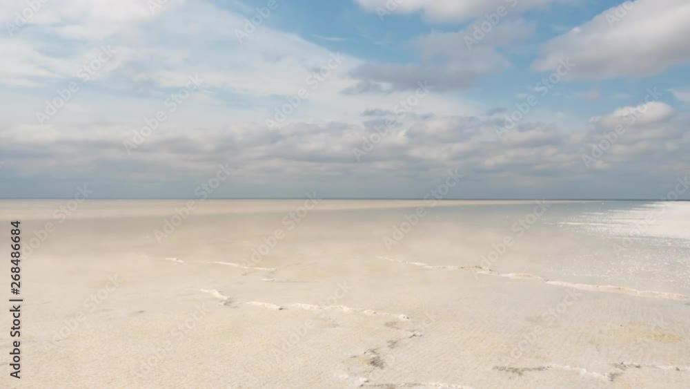 The beach of the salt lake with clouds reflected in the smooth water. The beach of the salt lake with clouds reflected in the smooth water.