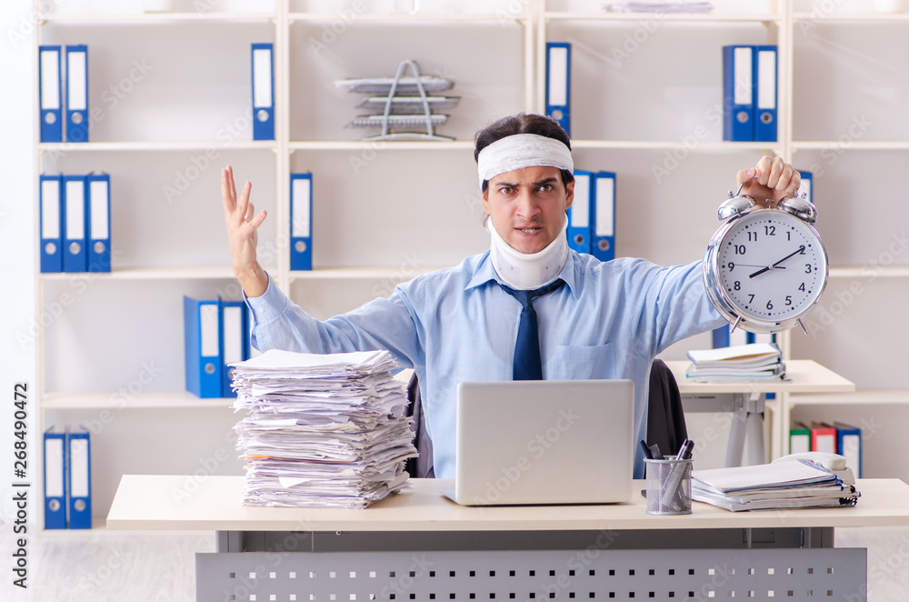Young injured male employee working in the office Young injured male employee working in the office