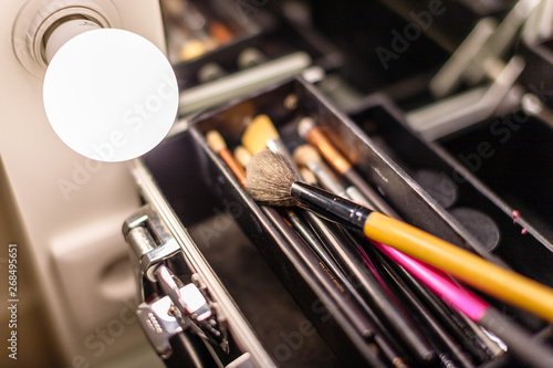 brushes for a make-up in a suitcase at a mirror in a dressing room