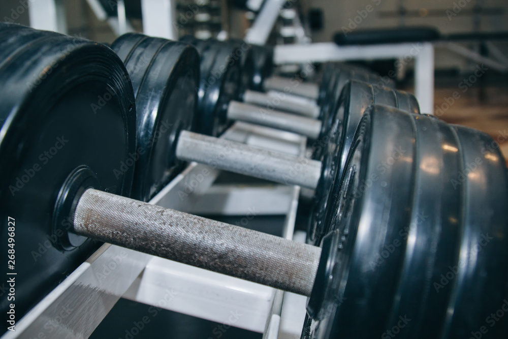 hand metal dumbbells lie together in a row on the rack in the gym close-up. training tools hand metal dumbbells lie together in a row on the rack in the gym close-up. training tools