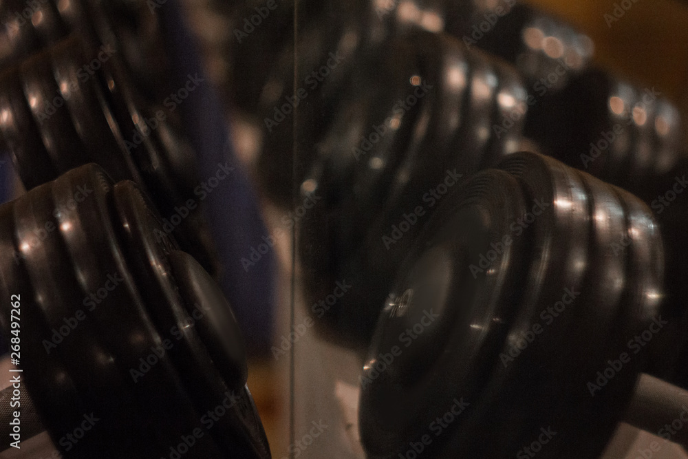 hand metal dumbbells lie together in a row on the rack in the gym close-up. training tools hand metal dumbbells lie together in a row on the rack in the gym close-up. training tools
