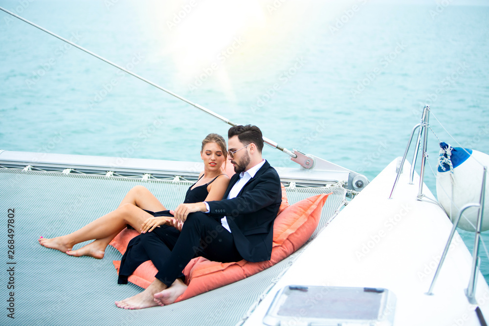 luxury business travelers sit on bean bag and showing their love for each other on a sailing boat. Concept business travel luxury business travelers sit on bean bag and showing their love for each other on a sailing boat. Concept business travel