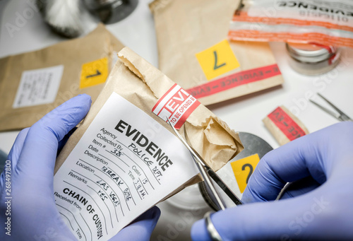 Scientific police opens with scissors a bag of evidence of a crime in scientific laboratory photo