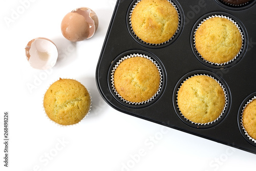 baked cupcake cakes in  a muffin tin and eggshells isolated with shadows on a white background, high angle view from above, copy space photo