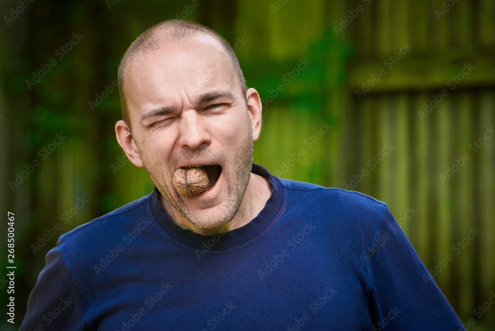 man trying to crack a nut with his teeth