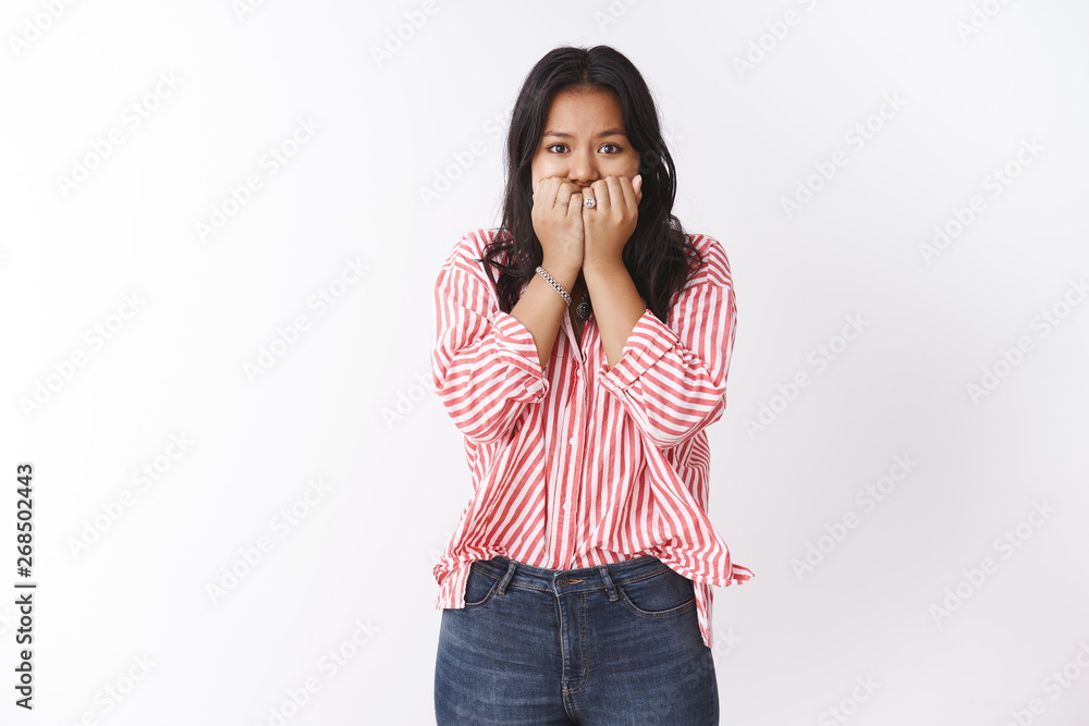 Insecure young woman scared be fired standing worried and frightened biting fingernails holding arms near mouth looking disturbed and nervous at camera, feeling anxiety over white background Insecure young woman scared be fired standing worried and frightened biting fingernails holding arms near mouth looking disturbed and nervous at camera, feeling anxiety over white background