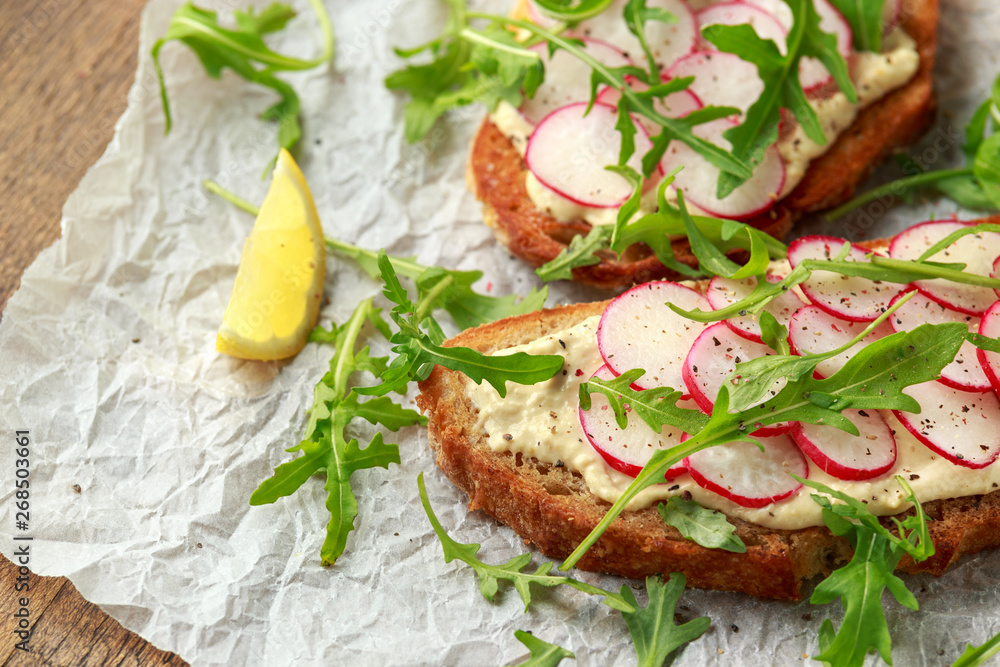 Hummus sourdough toast with reddish and wild rocket. Healthy vegan food Hummus sourdough toast with reddish and wild rocket. Healthy vegan food