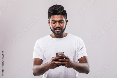 Handsome young indian man using mobile phone isolated on white background