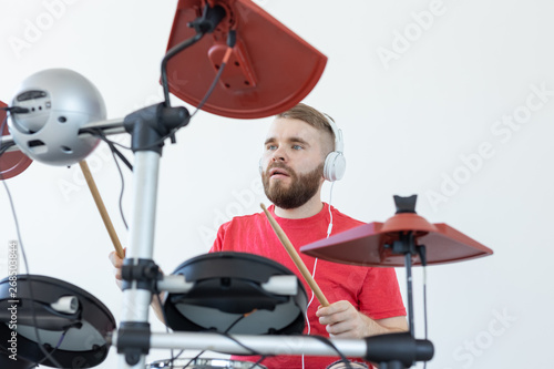 Drummer, hobbies and music concept - young man drummer in red shirt playing the electronic drums