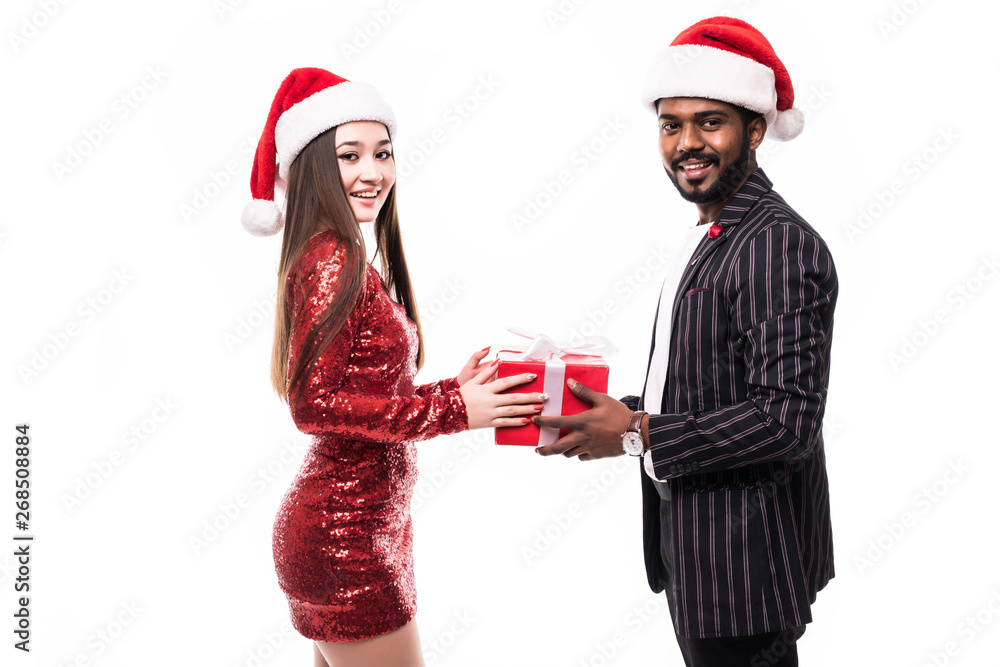 christmas holiday happy asian couple hold present gift box wear red new year santa hat cap, indian man and asian woman love smile looking at camera embracing, isolated over white background