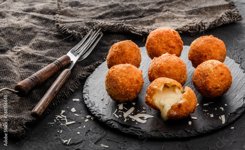 Quadro em tela Fried potato cheese balls or croquettes with spices on black plate over dark stone background