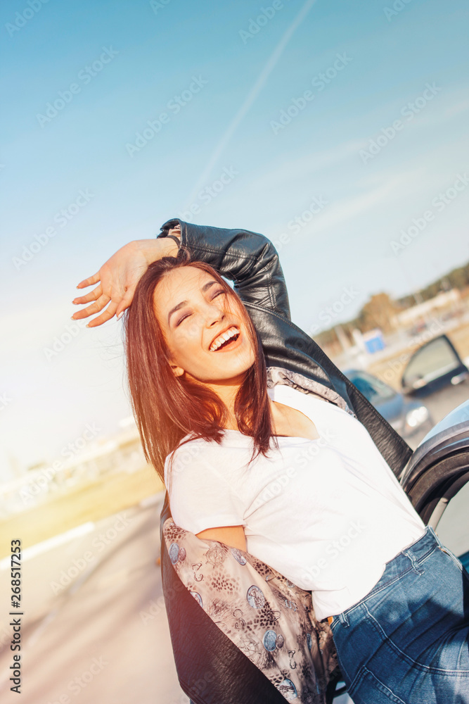 Happpy beautiful charming brunette long hair young asian woman in black leather jacket near her car Happpy beautiful charming brunette long hair young asian woman in black leather jacket near her car