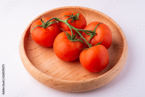 Tomato vegetables on wooden plate isolated on white