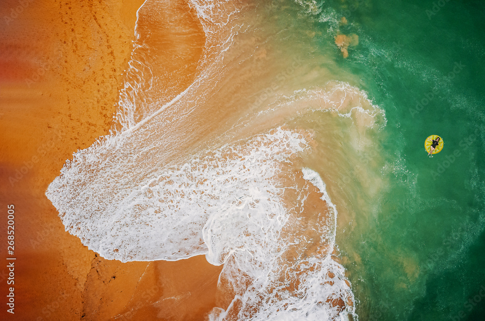 Fototapeta premium Aerial view of woman swimming on the yellow swim ring in the turquoise sea.. Top view from drone