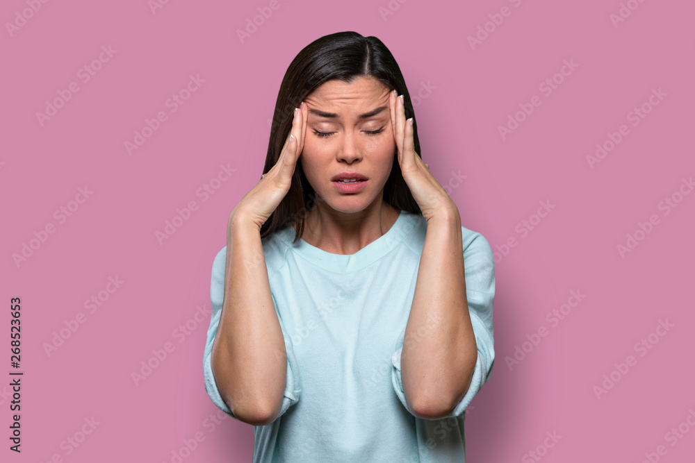 Woman overwhelmed with stress and concern, confusion and doubt, hands to head, on pink background Woman overwhelmed with stress and concern, confusion and doubt, hands to head, on pink background