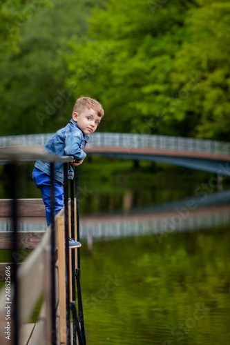 A little boy climbs a bridge railing in the park. The threat of drowning. Danger to children
