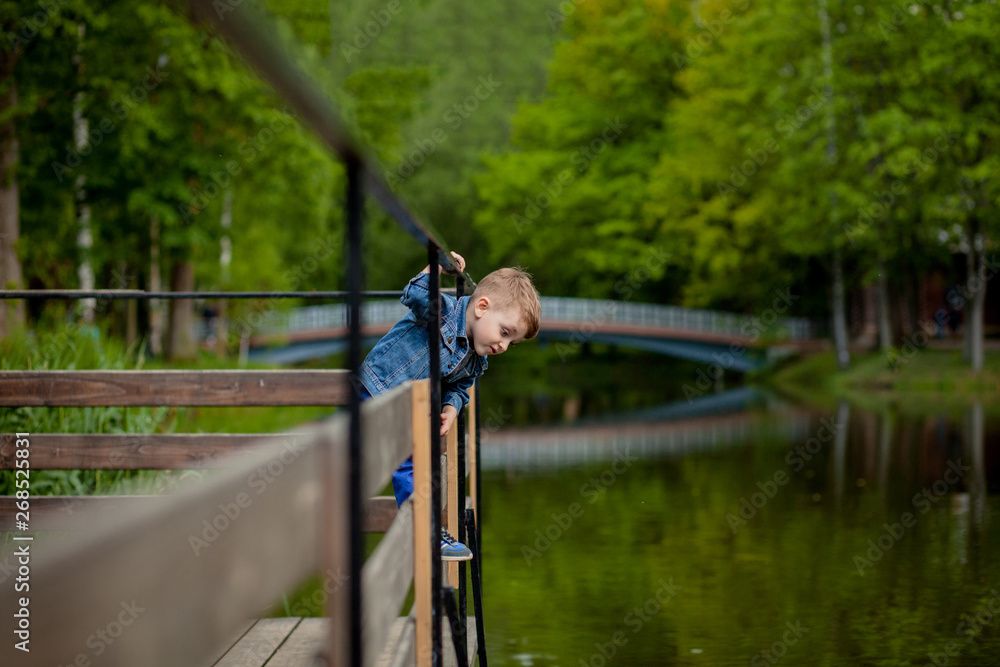 A little boy climbs a bridge railing in the park. The threat of drowning. Danger to children