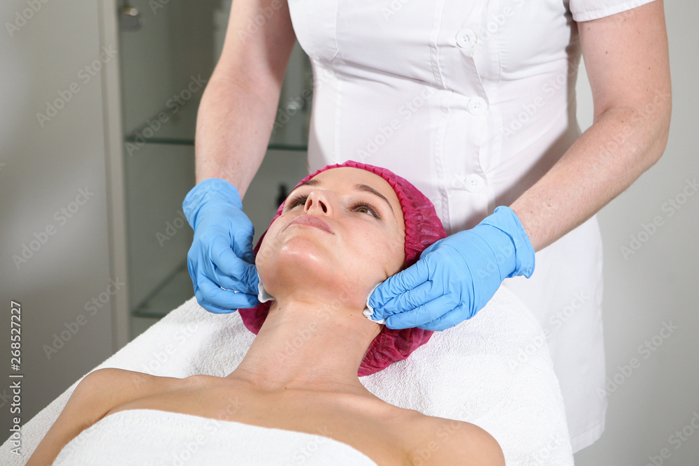 Obraz premium A cosmetologist puts a remedy on the face for the patient to nourish, moisturize and rejuvenate the skin. Cosmetic procedure in the clinic. Close-up of the patient's face.