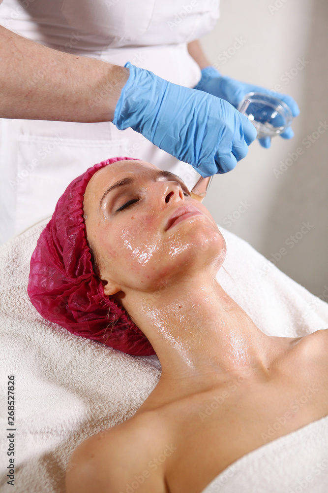 Close-up of the patient's face in the cosmetology office. Apply to the face means to moisturize and rejuvenate the skin. non-surgical facelift. Brush with the drug in the hands of a beautician.