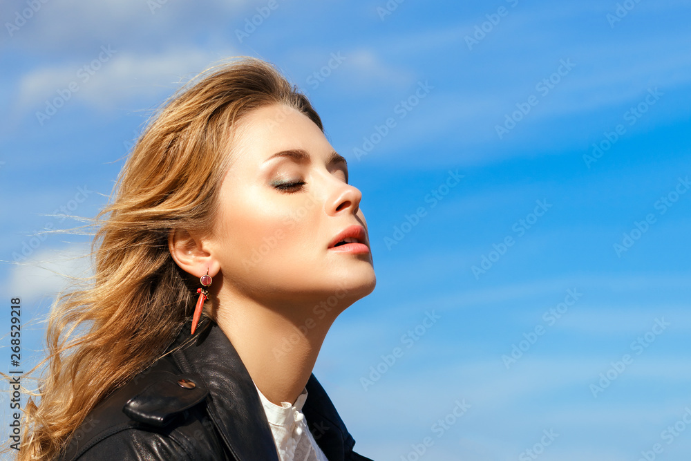 young beautiful blonde closed her eyes against bright blue sky young beautiful blonde closed her eyes against bright blue sky