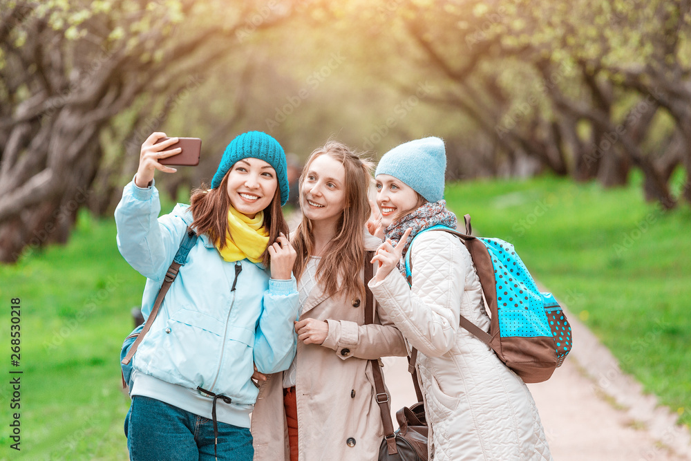 Three young pretty girls making selfie photo in spring park, sisterhood concept Three young pretty girls making selfie photo in spring park, sisterhood concept